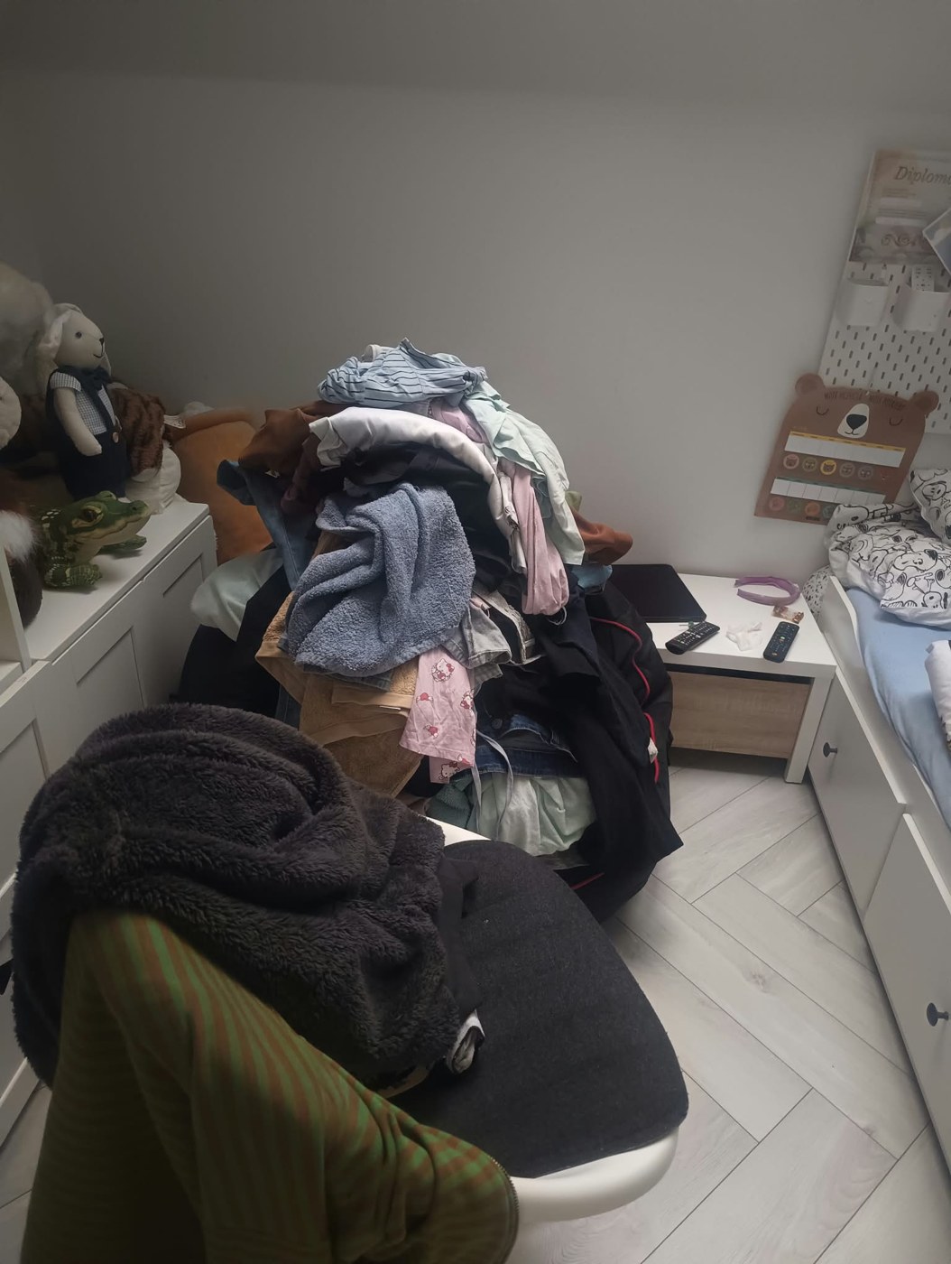 Duża sterta ubrań na fotelu w pokoju dziecięcym przed uporządkowaniem